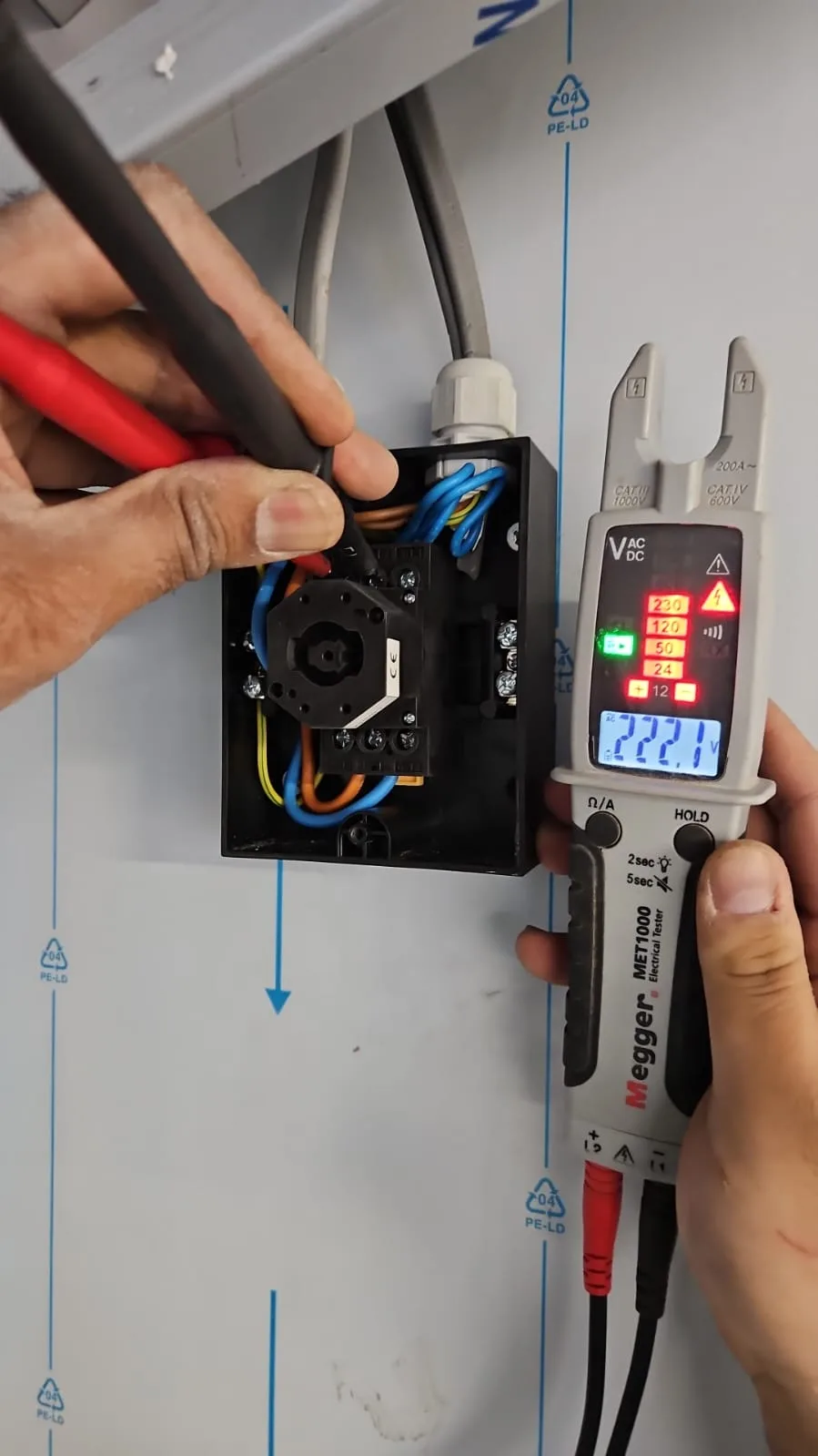 Voltage tester held beside an open appliance connection